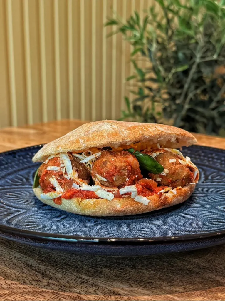 Puccia Puglia Burger - pain garni pugliese traditionnel avec des boulettes de viande à la sauce tomate fait par MadrePuglia Genève