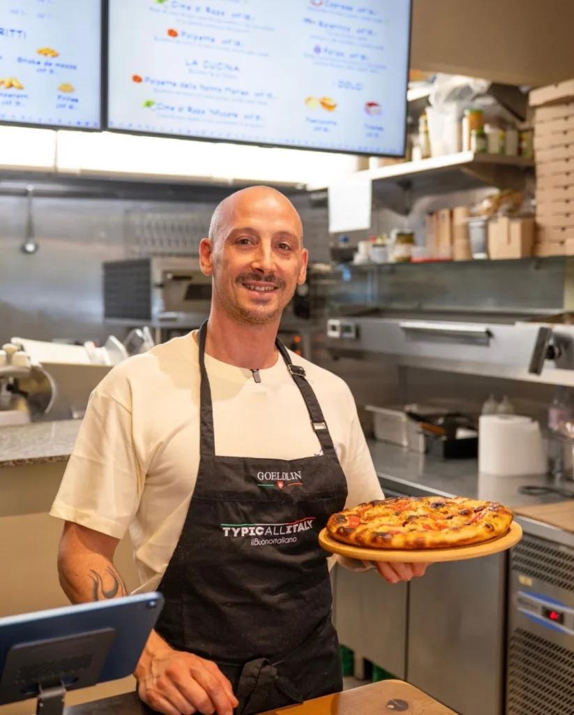 Chef Michele de MadrePuglia tenant une focaccia barese fraîchement sortie du four, en cuisine